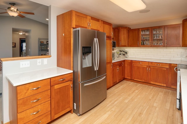 kitchen featuring light wood-type flooring, backsplash, stainless steel refrigerator with ice dispenser, and brown cabinetry