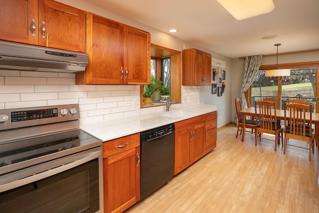 kitchen featuring a sink, light wood-style floors, stainless steel range with electric stovetop, dishwasher, and under cabinet range hood