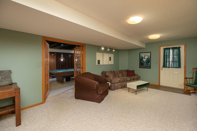 carpeted living room with track lighting, pool table, baseboards, and a textured ceiling