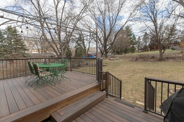 wooden terrace featuring outdoor dining space, a yard, and area for grilling