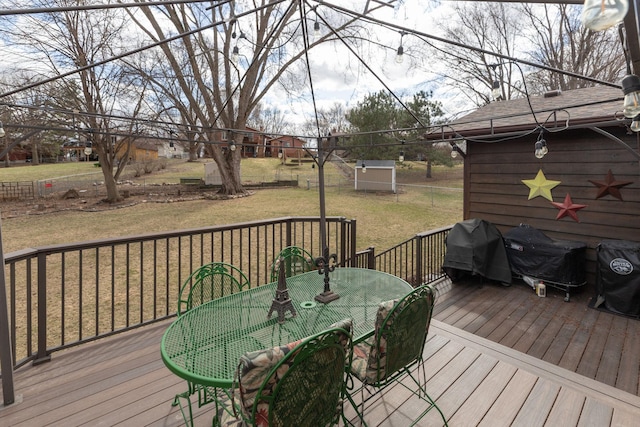 wooden terrace featuring outdoor dining area, a yard, and a grill