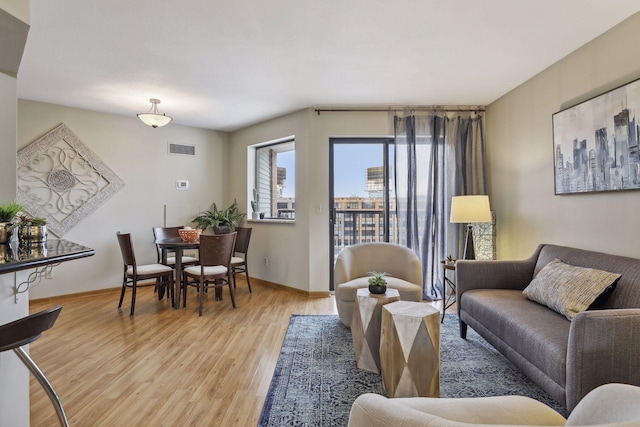 living room with baseboards, light wood finished floors, and visible vents