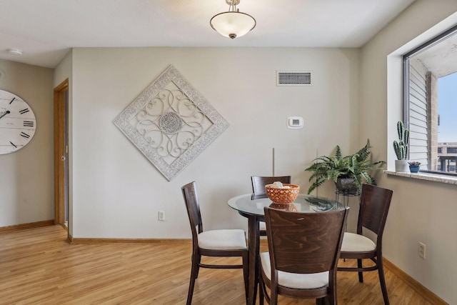 dining area with baseboards, light wood-type flooring, and visible vents