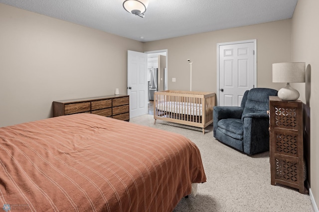 bedroom featuring freestanding refrigerator, a textured ceiling, and light colored carpet