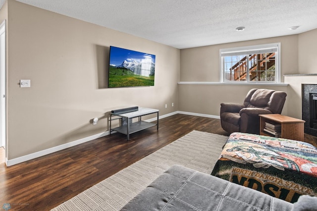 living room with a textured ceiling, baseboards, wood finished floors, and a fireplace