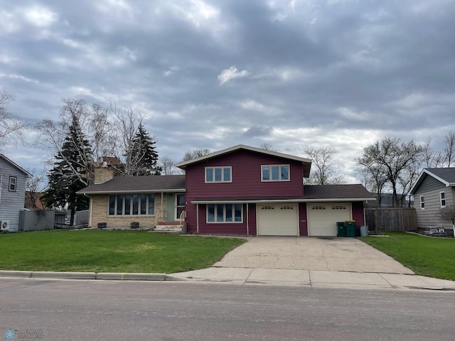 split level home featuring a front lawn, fence, a chimney, and concrete driveway