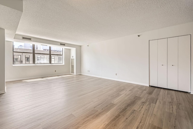 401 1st St Unit 414, Minneapolis, MN 55401 - unfurnished living room featuring a textured ceiling, light wood-style floors, and baseboards