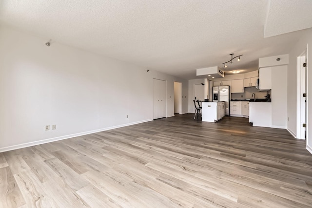 401 1st St Unit 414, Minneapolis, MN 55401 - unfurnished living room featuring a textured ceiling, wood finished floors, baseboards, and a sink