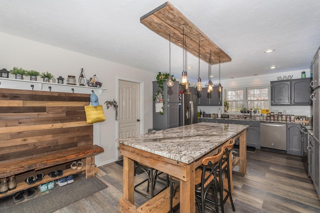kitchen with gray cabinets, light stone countertops, stainless steel appliances, and dark wood-type flooring