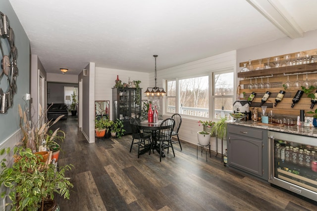 dining room with wine cooler, a bar, dark wood-style flooring, and wooden walls