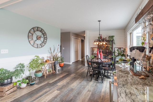 dining area featuring wooden walls, wood finished floors, and a notable chandelier