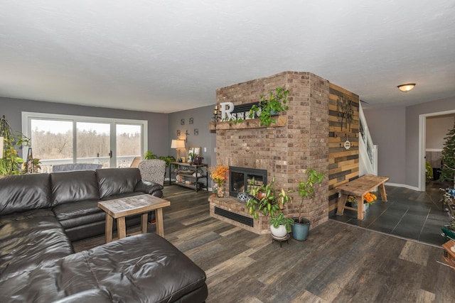 living room with baseboards, a textured ceiling, wood finished floors, and a fireplace