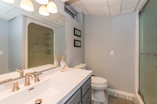 bathroom with vanity, a shower stall, a drop ceiling, and toilet