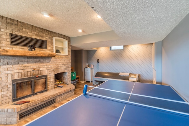 playroom with wooden walls, a textured ceiling, and a fireplace