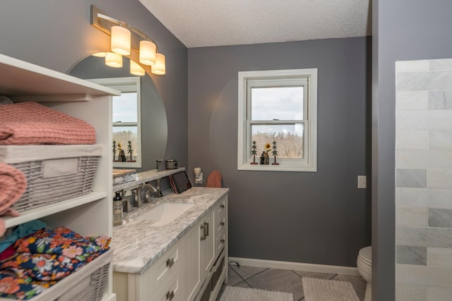 bathroom with a healthy amount of sunlight, vanity, toilet, and a textured ceiling