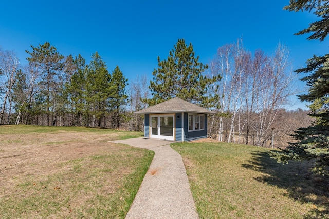 bungalow-style home featuring a front lawn and an outbuilding