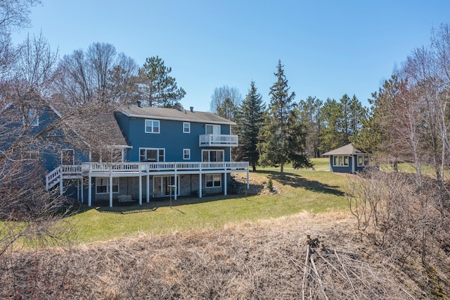 back of house featuring a lawn, a wooden deck, an outdoor structure, and a balcony
