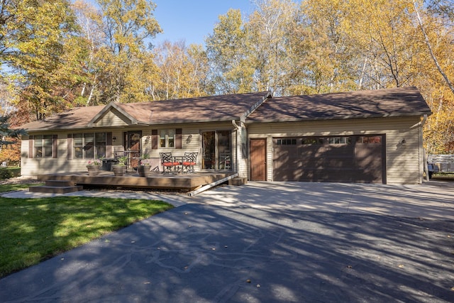 single story home with covered porch, driveway, and a garage