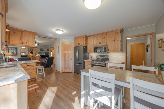 kitchen with light countertops, appliances with stainless steel finishes, decorative backsplash, and light wood-style floors
