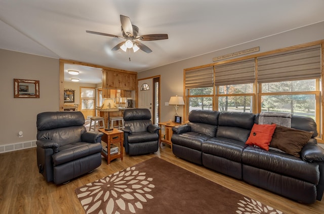 living room with ceiling fan, visible vents, and wood finished floors
