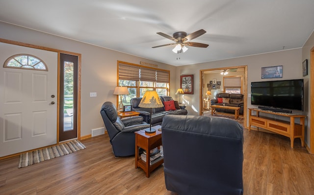 living room with visible vents, light wood-style floors, ceiling fan, and baseboards