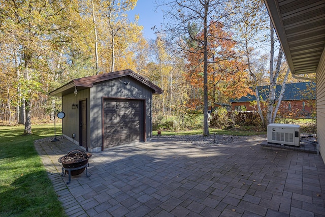 view of patio featuring a garage, an outbuilding, and an outdoor fire pit