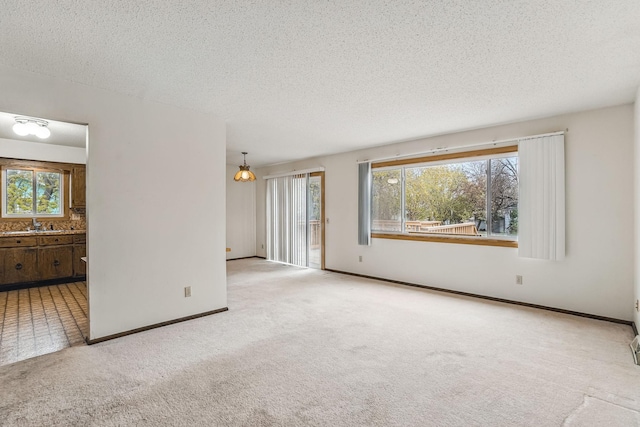 unfurnished living room featuring carpet floors, a textured ceiling, and baseboards