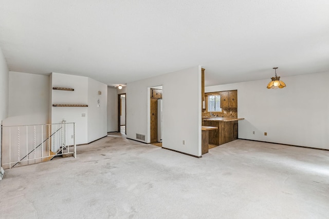 unfurnished living room with light colored carpet, baseboards, and visible vents