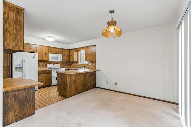 kitchen featuring a sink, white appliances, brown cabinetry, a peninsula, and decorative backsplash