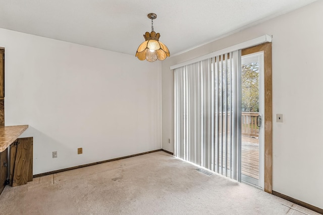 unfurnished dining area featuring baseboards, visible vents, and light carpet