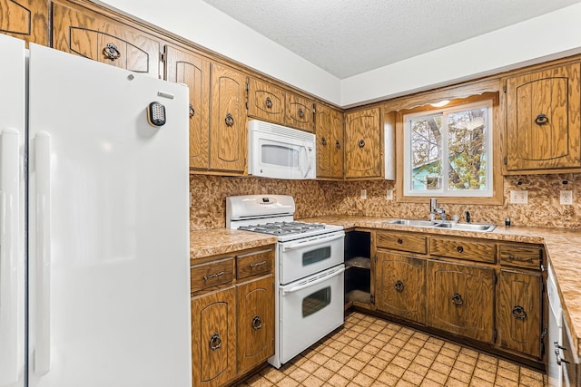 kitchen with white appliances, light countertops, a textured ceiling, a sink, and backsplash