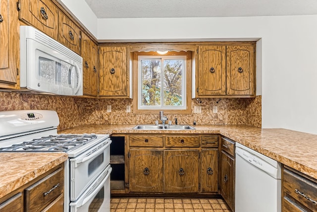 kitchen with a sink, light countertops, decorative backsplash, and white appliances
