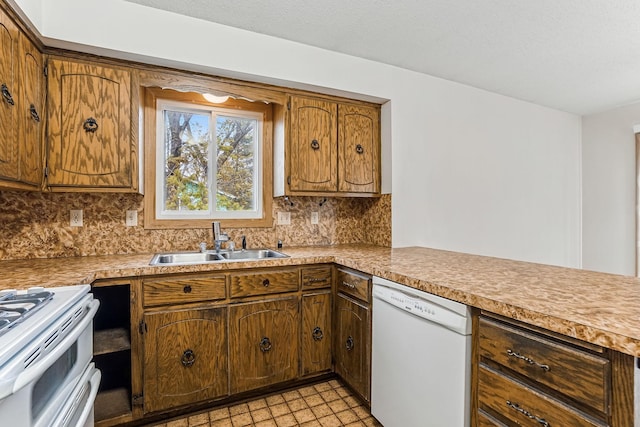 kitchen with a sink, backsplash, white appliances, and light countertops