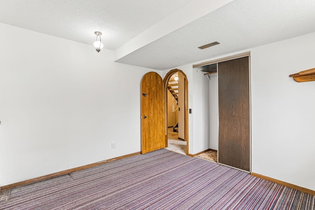 carpeted spare room featuring baseboards, stairs, a textured ceiling, and visible vents