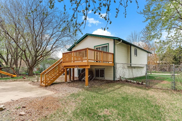 rear view of house with a wooden deck, a gate, fence, a yard, and stairs