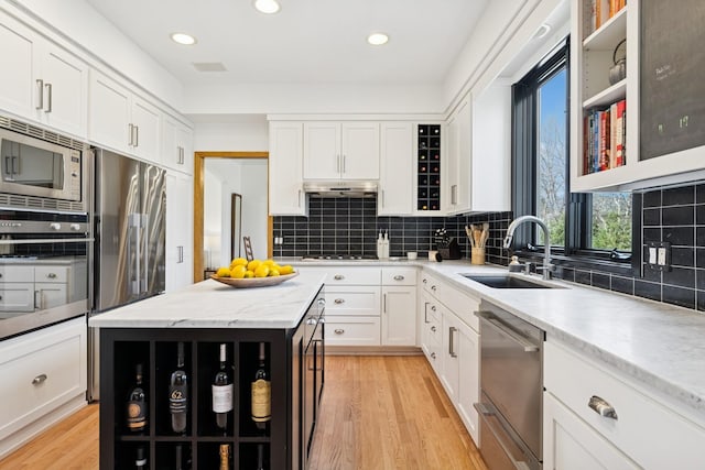 3412 Williamsburg Pkwy, Woodbury, MN 55129 - kitchen featuring backsplash, white cabinetry, a sink, stainless steel appliances, and light wood-style flooring