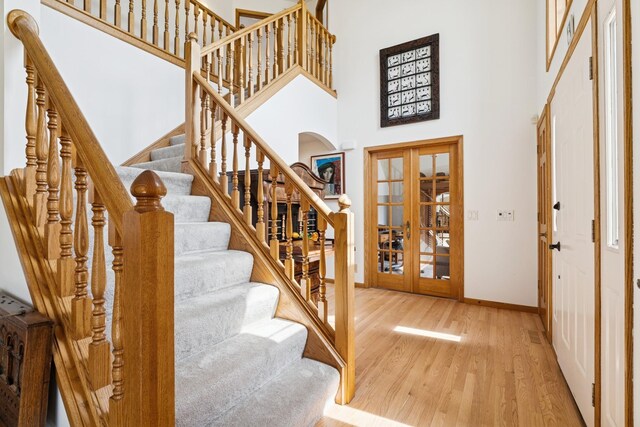 3412 Williamsburg Pkwy, Woodbury, MN 55129 - foyer entrance featuring a high ceiling, arched walkways, french doors, baseboards, and wood finished floors