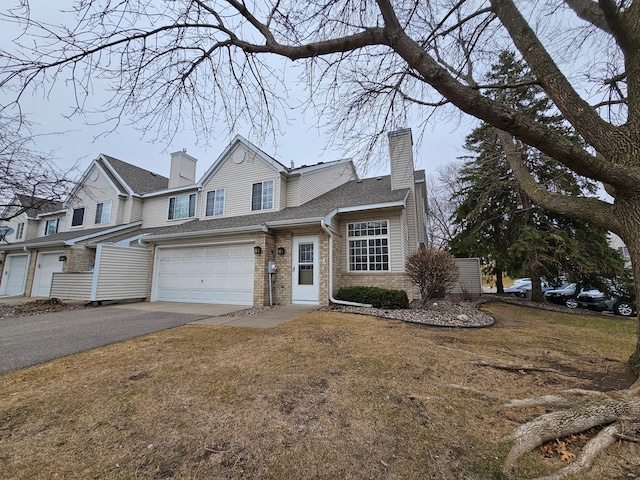 view of front of house with a chimney, an attached garage, brick siding, and aphalt driveway