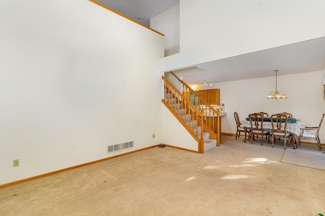 living room with carpet flooring, a notable chandelier, baseboards, visible vents, and stairway