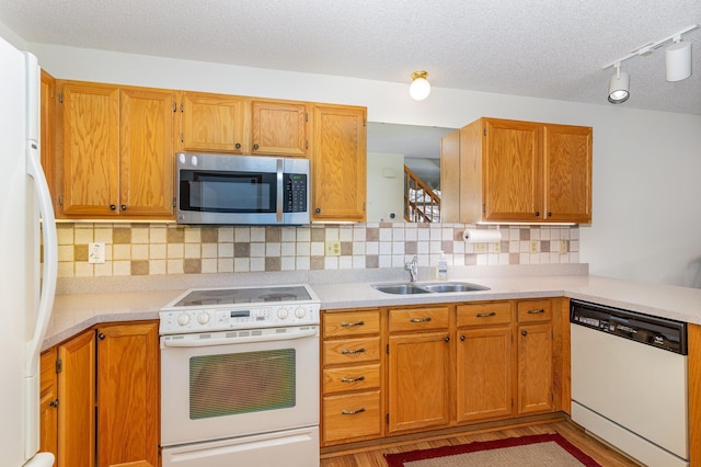 kitchen featuring white appliances, light countertops, tasteful backsplash, a sink, and light wood-style flooring