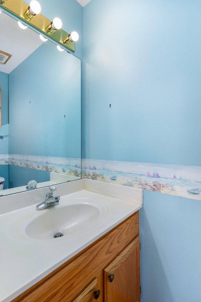 bathroom featuring vanity, visible vents, and toilet