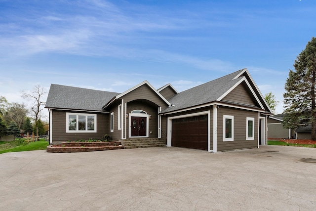 ranch-style home with an attached garage, driveway, and a shingled roof
