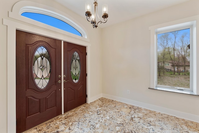 foyer entrance featuring baseboards, plenty of natural light, and a chandelier