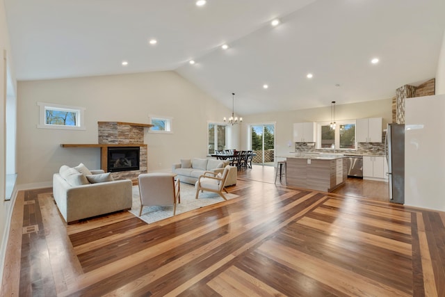 living room featuring an inviting chandelier, light wood-style floors, a fireplace, and recessed lighting
