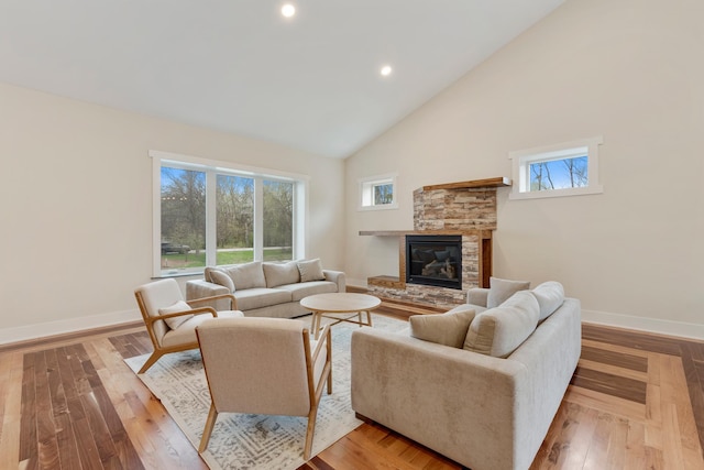 living area with a stone fireplace, recessed lighting, baseboards, and high vaulted ceiling