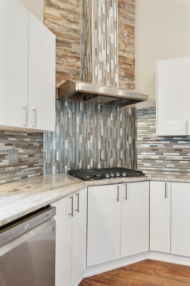 kitchen featuring light stone counters, white cabinets, backsplash, and stainless steel appliances