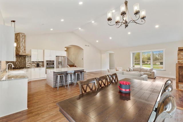 dining room with arched walkways, recessed lighting, visible vents, and light wood-type flooring