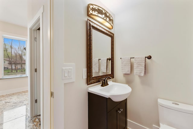 bathroom featuring baseboards, toilet, and vanity