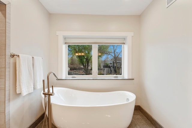 bathroom featuring baseboards, a soaking tub, and visible vents