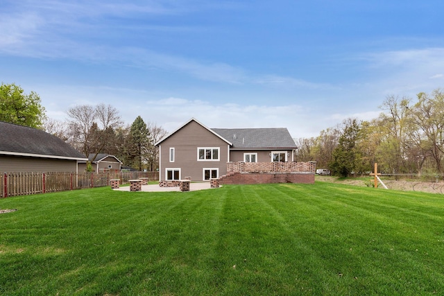 back of property featuring an outdoor fire pit, fence, and a yard